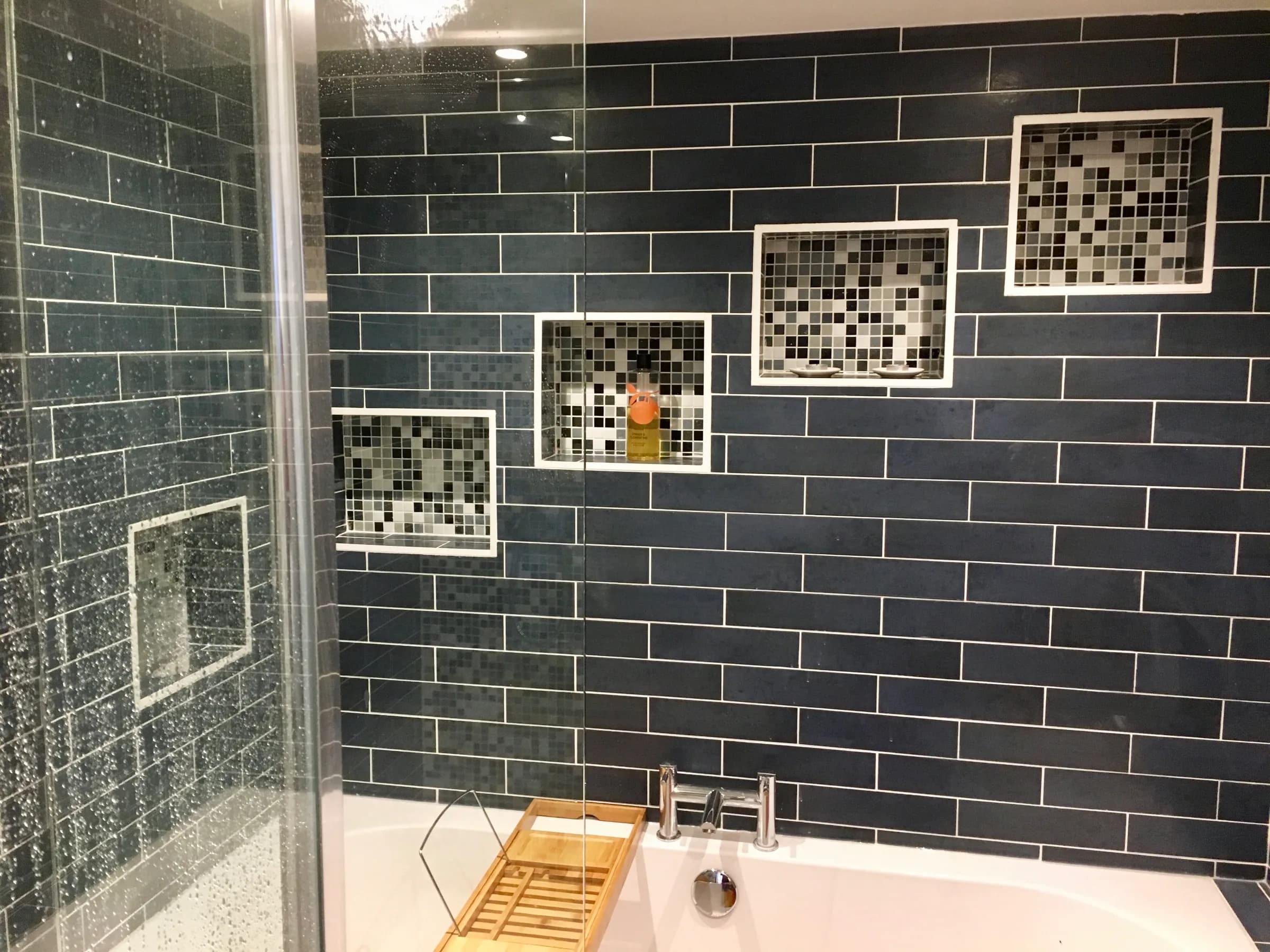 Bathroom tiled in dark brick tiles with mosaic recesses