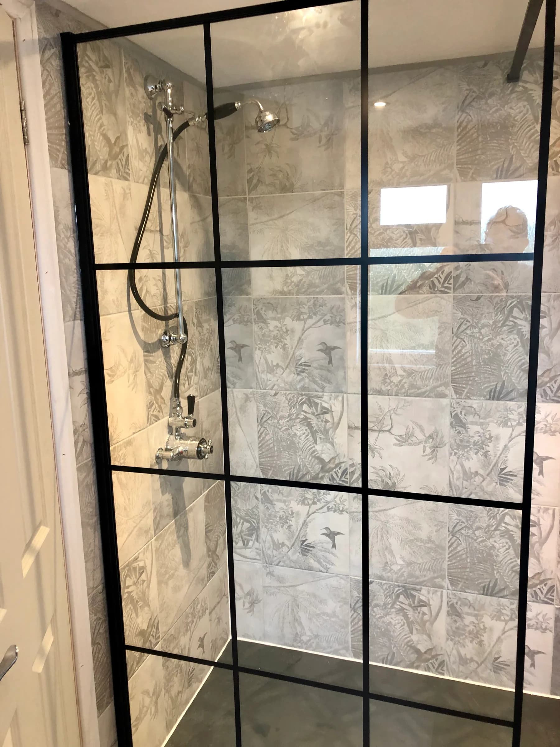 Walk-in shower fitted with black framed glass screen